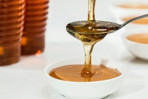 honey being poured in a cup to be used as ahome remedy for tooth pain relief at home