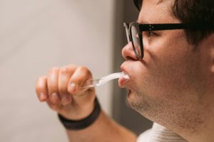 man brushing his teeth to maintain oral hygiene